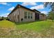 A green backyard featuring a hose, along with a view of the screened patio and the home's exterior at 4155 Barletta Ct, Wesley Chapel, FL 33543