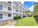 Exterior of condo building featuring a well manicured lawn and beautiful palm trees at 4801 Airport Rd # 211, Zephyrhills, FL 33542