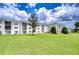 Exterior view of a multi-story building featuring lush green lawns and well-maintained landscaping and a cloudy sky at 4801 Airport Rd # 211, Zephyrhills, FL 33542