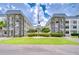 Low angle view of a condo building with green grass, well maintained landscaping, and an American flag in front of the building at 4801 Airport Rd # 211, Zephyrhills, FL 33542