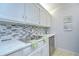 Kitchen featuring white cabinets, stainless steel sink, faucet and appliances, and tile backsplash at 4801 Airport Rd # 211, Zephyrhills, FL 33542