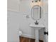 Clean and modern half bathroom featuring a pedestal sink, updated lighting, and decorative wall paneling at 4918 Stolls Ave, Tampa, FL 33615