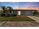 Attractive single-story home at sunset with a well-kept lawn and mature palm trees in the front yard at 5377 Springwood Blvd, Pinellas Park, FL 33782