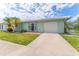 Inviting single-story home with lush lawn, mature palm trees, and a convenient attached garage at 5377 Springwood Blvd, Pinellas Park, FL 33782