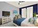 Stylishly decorated bedroom featuring a queen bed, blue accent wall, television, and decorative furniture at 6361 92Nd N Pl # 1704, Pinellas Park, FL 33782