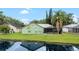 View of the backyard of the home, featuring a screened-in patio, lush green grass, and serene water view at 6621 Appaloosa Dr, Tampa, FL 33625