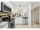 Well-lit kitchen features stainless steel appliances, stone backsplash, white cabinets, and tile flooring at 6630 Spring Flower Dr # 14, New Port Richey, FL 34653