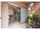 View of a tiled patio area with seating, mature plants and sliding glass doors to the kitchen at 6630 Spring Flower Dr # 14, New Port Richey, FL 34653