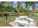 Outdoor picnic area with a grill, stone table and benches surrounded by mature trees at 6630 Spring Flower Dr # 14, New Port Richey, FL 34653
