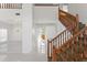 Bright open foyer with wooden staircase and banister, elegant chandelier and seamless white tile flooring at 7114 Pelican Island Dr, Tampa, FL 33634