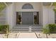 Stylish front entry with a gray double door with keystone window, and manicured bushes at 7114 Pelican Island Dr, Tampa, FL 33634