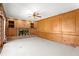 Open living room features wood paneling, brick fireplace with shelving, and large windows overlooking the backyard at 7114 Pelican Island Dr, Tampa, FL 33634