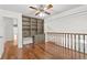 Open loft area with hardwood floors, built-in shelves and cabinets, and a ceiling fan at 7114 Pelican Island Dr, Tampa, FL 33634