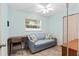Light blue bedroom featuring tile floors, a ceiling fan, a blue loveseat with decorative pillows, and a window at 7276 21St Street N, St Petersburg, FL 33702
