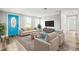 Bright living room with a blue front door, neutral furniture, and large windows at 7804 Bracken Dr, Port Richey, FL 34668