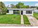 Charming single-story home featuring a manicured lawn, clean white exterior, and stylish black-framed windows and door at 7930 Jeffery Ave, North Port, FL 34287