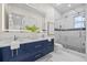 Modern bathroom featuring double sinks, sleek blue cabinets, and a glass-enclosed shower with stylish tile at 820 Bay Point Dr, Madeira Beach, FL 33708