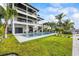 Expansive, modern three-story home with a pool, a lush lawn, and balconies overlooking the water at 820 Bay Point Dr, Madeira Beach, FL 33708
