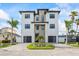 Beautifully designed three-story home with dual garages, stone accents, and a well-manicured front yard at 820 Bay Point Dr, Madeira Beach, FL 33708