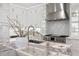 Close-up of a modern kitchen island with marble countertop, a stainless steel range hood, and white cabinetry at 820 Bay Point Dr, Madeira Beach, FL 33708
