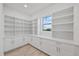 Walk-in pantry with custom shelving, cabinetry, and a window providing natural light and organization at 820 Bay Point Dr, Madeira Beach, FL 33708