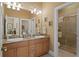 Bathroom with dual sink vanity, granite countertops, and a tiled walk-in shower at 3118 W Bay Villa Ave, Tampa, FL 33611