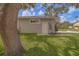 A glimpse of the property's side featuring a well-kept lawn, partial view of house, and a mature shade tree at 102 7Th Se Ave, Largo, FL 33771