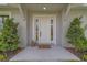 Close-up of front door with sidelights, decorative lanterns, and manicured landscaping on a covered front porch at 102 7Th Se Ave, Largo, FL 33771