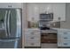 Close up of kitchen area showcasing stainless steel appliances, mosaic backsplash, and white cabinets at 102 7Th Se Ave, Largo, FL 33771