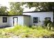 Exterior of home featuring an overgrown yard, modern black window trim, and two doors at 1109 N Obrien St, Tampa, FL 33607