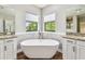 Elegant bathroom with a freestanding tub, dual sinks, granite counters, and wood-style flooring at 11407 Drifting Leaf Dr, Riverview, FL 33579