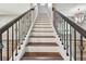 Traditional staircase featuring dark wood handrails and decorative iron balusters at 11407 Drifting Leaf Dr, Riverview, FL 33579