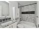 Modern bathroom featuring marble-look tile, updated vanity with granite counters, and shower-tub combo at 1311 W Perdiz St, Tampa, FL 33612