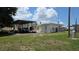 View of the home with carport and vehicle, surrounded by a well maintained lawn and blue sky at 13330 Fort King Rd, Dade City, FL 33525