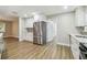 Well-lit kitchen with stainless steel refrigerator, white cabinets, mosaic backsplash, and wood floors at 1410 Moss Laden Ct, Brandon, FL 33511