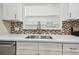 Close-up of a kitchen sink with mosaic backsplash, white cabinets, and modern faucet at 1410 Moss Laden Ct, Brandon, FL 33511