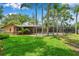 Expansive backyard featuring a screened-in pool, lush lawn and mature landscaping, ideal for outdoor living and entertaining at 1695 Cinnamon Ln, Dunedin, FL 34698