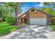 Charming home with a two-car garage, complemented by mature landscaping and a beautiful shade tree at 1695 Cinnamon Ln, Dunedin, FL 34698