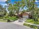 Charming home with a manicured lawn, mature trees, and a two car garage at 1695 Cinnamon Ln, Dunedin, FL 34698