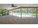 Covered patio with brick pavers, ceiling fans, and views of a sparkling screened-in pool and tropical landscaping at 1695 Cinnamon Ln, Dunedin, FL 34698