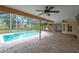 Inviting screened-in pool area with brick pavers, ceiling fans, and lush landscaping creating a private oasis at 1695 Cinnamon Ln, Dunedin, FL 34698