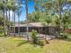 View of the screened-in pool and spa surrounded by tropical landscaping, trees, and a spacious patio area at 1695 Cinnamon Ln, Dunedin, FL 34698