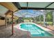 Beautiful in-ground pool under screened lanai with brick paver deck and view of tropical backyard at 1695 Cinnamon Ln, Dunedin, FL 34698