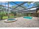 Screened-in pool and spa surrounded by brick pavers and lush landscaping, creating a private backyard retreat at 1695 Cinnamon Ln, Dunedin, FL 34698