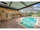 Screened-in pool features brick paved deck, in-ground spa, ceiling fans, and access to backyard at 1695 Cinnamon Ln, Dunedin, FL 34698