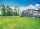 The backyard's lush green lawn with a white fence offers a view of the home's screened-in pool area at 18079 Romanesque Ct, Spring Hill, FL 34610