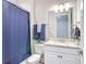 Bright bathroom featuring a white vanity with granite countertop, updated fixtures, and a blue shower curtain at 18079 Romanesque Ct, Spring Hill, FL 34610
