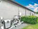 A gray home exterior features an outdoor utilities area enclosed by manicured greenery at 18079 Romanesque Ct, Spring Hill, FL 34610