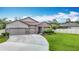 Charming single-story home featuring a well-manicured lawn, three-car garage, and stone accents at 18079 Romanesque Ct, Spring Hill, FL 34610