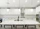 Bright kitchen boasts white cabinets, granite counters, subway tile backsplash, and stainless steel hood at 18079 Romanesque Ct, Spring Hill, FL 34610